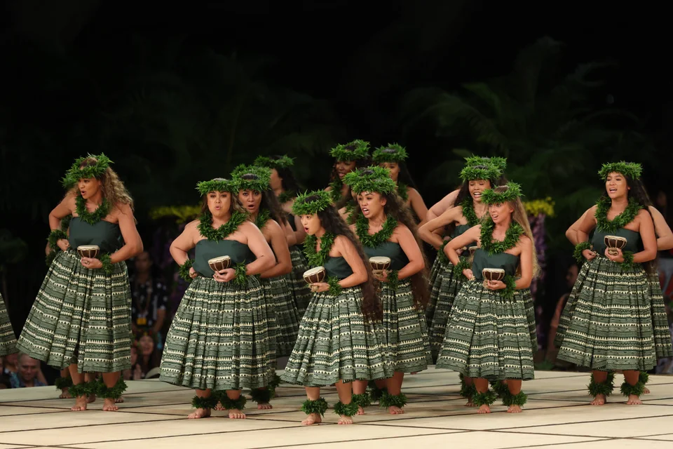 A group of dancers kneeling in formation during a hula performance.